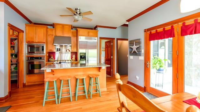 kitchen with ceiling fan, light wood-type flooring, a kitchen island, and built in appliances