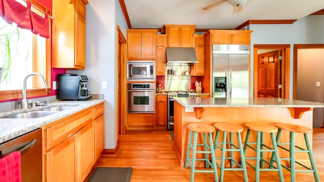 kitchen with built in appliances, light hardwood / wood-style floors, a center island, and wall chimney exhaust hood