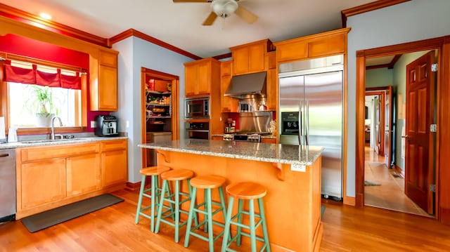 kitchen featuring built in appliances, light hardwood / wood-style flooring, a center island, and sink