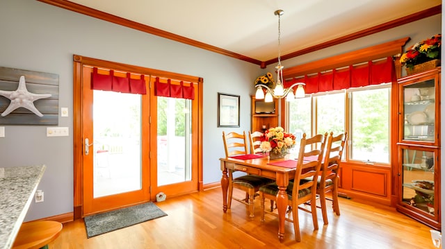 dining space featuring a notable chandelier, crown molding, and light hardwood / wood-style flooring