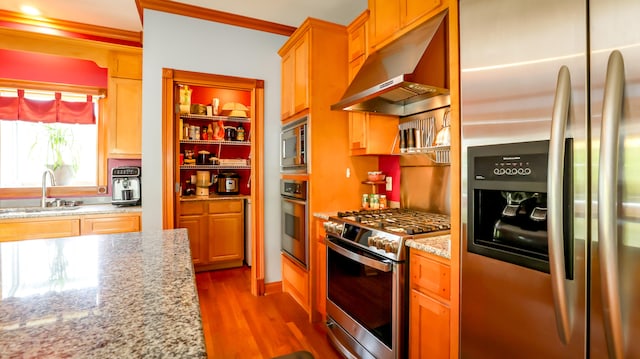 kitchen featuring appliances with stainless steel finishes, light stone countertops, light hardwood / wood-style floors, ornamental molding, and sink