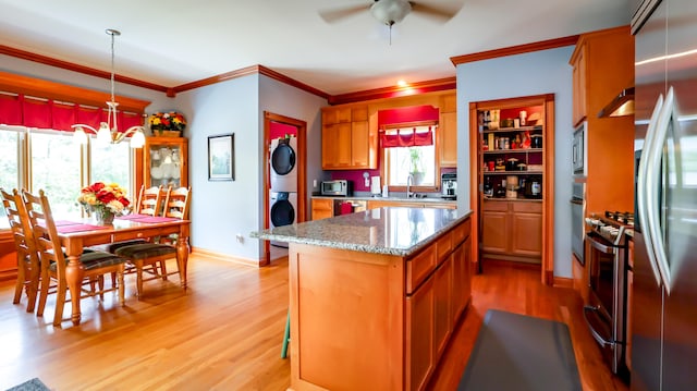 kitchen featuring appliances with stainless steel finishes, light hardwood / wood-style floors, a center island, ceiling fan, and decorative light fixtures