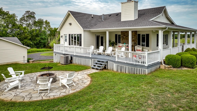 back of property featuring a patio area, a lawn, central AC unit, and an outdoor fire pit