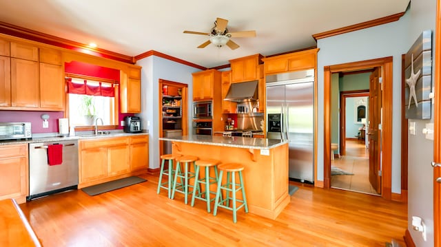 kitchen featuring built in appliances, ceiling fan, sink, light hardwood / wood-style flooring, and a center island