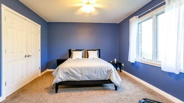 carpeted bedroom with ceiling fan, a closet, and multiple windows