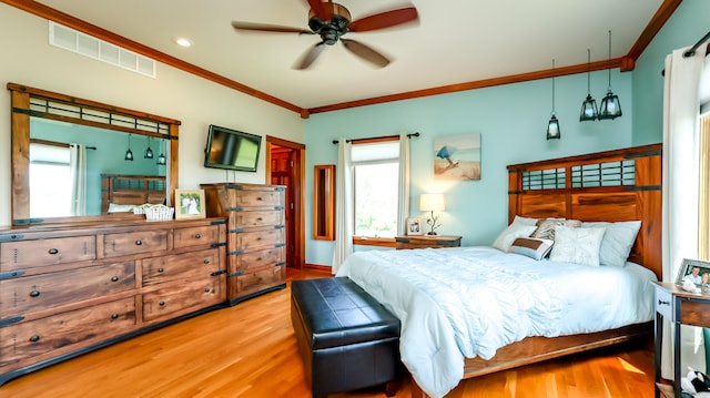 bedroom featuring ceiling fan, light wood-type flooring, multiple windows, and crown molding