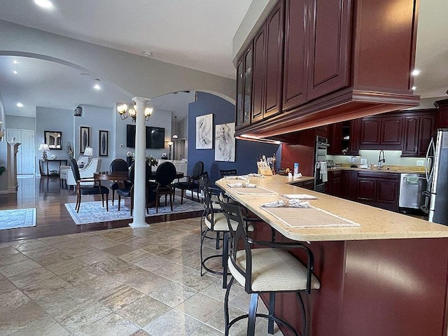 kitchen featuring dishwasher, a kitchen breakfast bar, a peninsula, double wall oven, and a sink