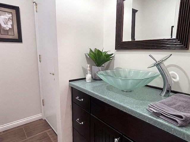 bathroom with baseboards, wood finished floors, and vanity