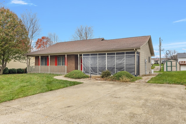 view of front of property with a sunroom, a front lawn, covered porch, and a storage unit