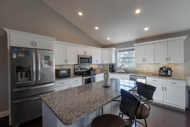 kitchen with sink, white cabinetry, a center island, appliances with stainless steel finishes, and light stone countertops