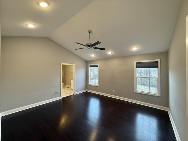 empty room with dark hardwood / wood-style flooring, vaulted ceiling, and ceiling fan