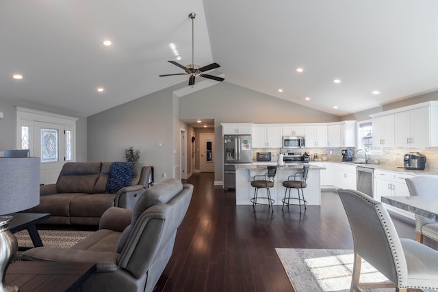 living room featuring ceiling fan, lofted ceiling, sink, and dark hardwood / wood-style flooring