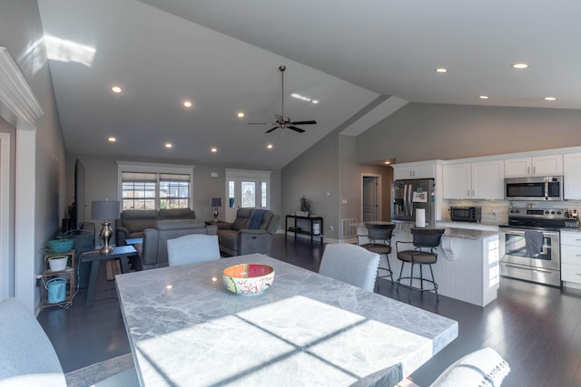 dining space with dark wood-type flooring, ceiling fan, and high vaulted ceiling