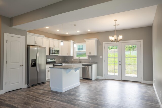 kitchen with white cabinetry, decorative light fixtures, stainless steel appliances, and a kitchen island