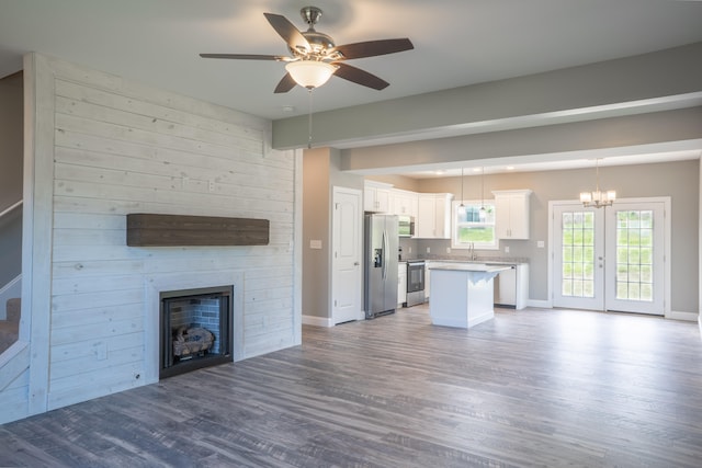 unfurnished living room featuring sink, ceiling fan with notable chandelier, light hardwood / wood-style floors, and a large fireplace