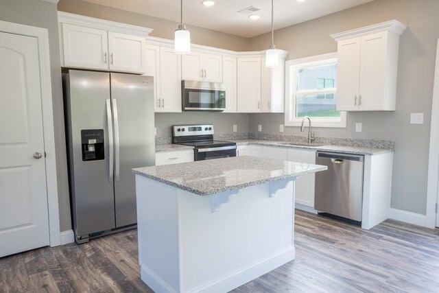 kitchen featuring sink, light stone counters, appliances with stainless steel finishes, a kitchen island, and white cabinets