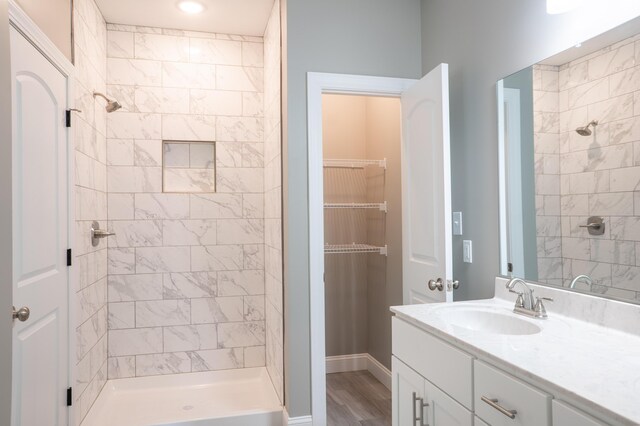 bathroom with vanity, wood-type flooring, and a tile shower