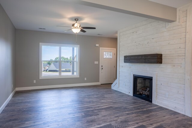 unfurnished living room featuring ceiling fan, a large fireplace, and dark hardwood / wood-style flooring