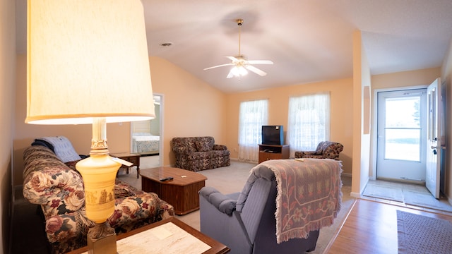 living room with ceiling fan, light hardwood / wood-style flooring, and vaulted ceiling