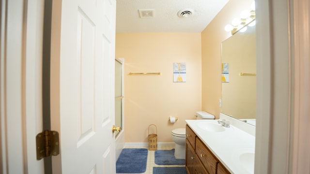 full bathroom featuring a textured ceiling, shower / bath combination with glass door, toilet, tile patterned floors, and dual vanity