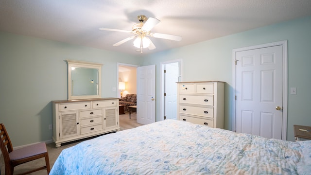 bedroom featuring ceiling fan, ensuite bath, and light colored carpet