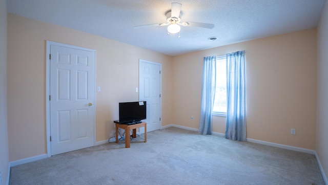 carpeted bedroom featuring ceiling fan and a textured ceiling