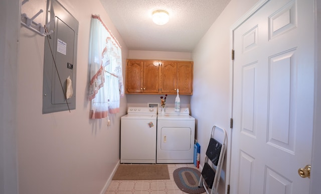 washroom with a textured ceiling, electric panel, cabinets, light tile patterned flooring, and washer and clothes dryer