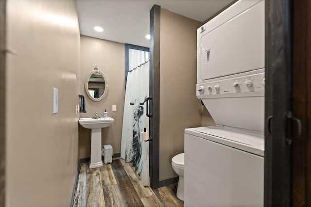 washroom featuring stacked washer / drying machine, sink, and wood-type flooring