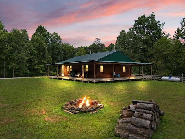 view of front of home with a fire pit and a lawn