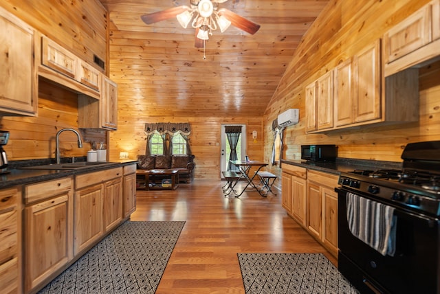 kitchen featuring ceiling fan, an AC wall unit, wooden walls, light hardwood / wood-style floors, and black appliances