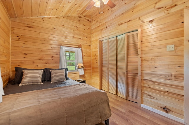 unfurnished bedroom featuring hardwood / wood-style floors, wooden walls, a closet, ceiling fan, and wooden ceiling