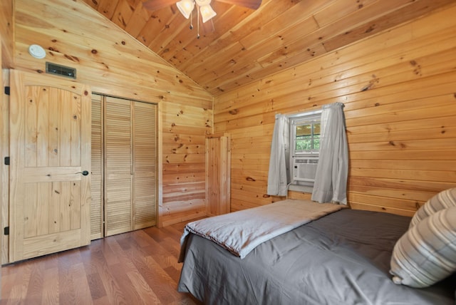 bedroom featuring hardwood / wood-style floors, vaulted ceiling, wooden walls, a closet, and ceiling fan