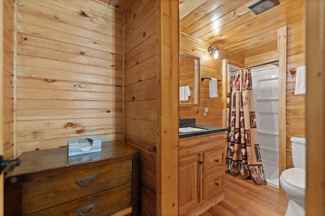 full bathroom with wood walls, wood-type flooring, vanity, wood ceiling, and toilet