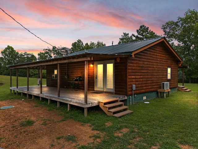 back house at dusk featuring a wooden deck, central AC, and a yard