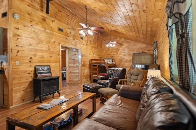 living room featuring ceiling fan, hardwood / wood-style floors, wood ceiling, and a wood stove