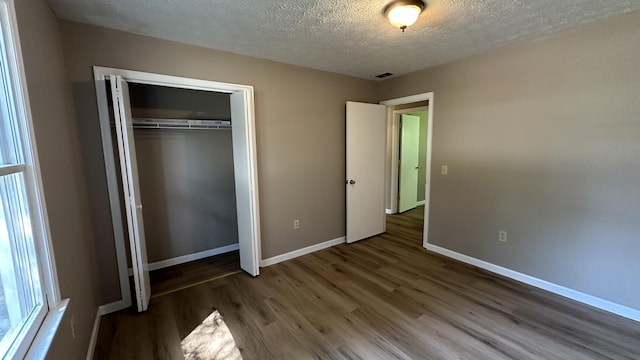 unfurnished bedroom featuring dark wood-type flooring, a closet, and a textured ceiling