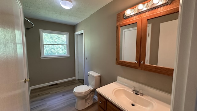 bathroom with vanity, toilet, hardwood / wood-style floors, and a textured ceiling