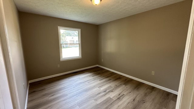 empty room with hardwood / wood-style flooring and a textured ceiling