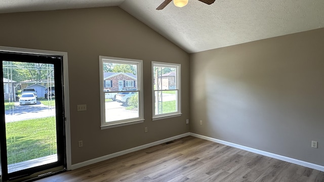 doorway to outside with lofted ceiling, a textured ceiling, and light wood-type flooring