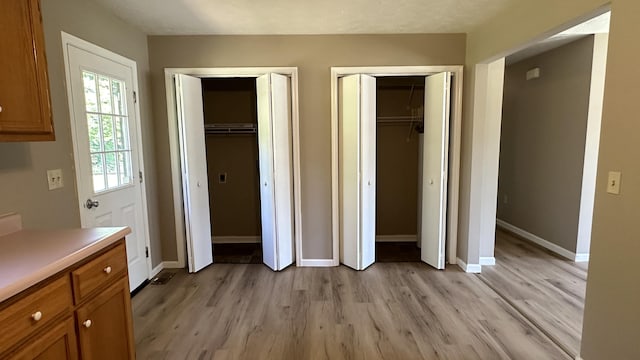 unfurnished bedroom featuring light hardwood / wood-style flooring and multiple closets