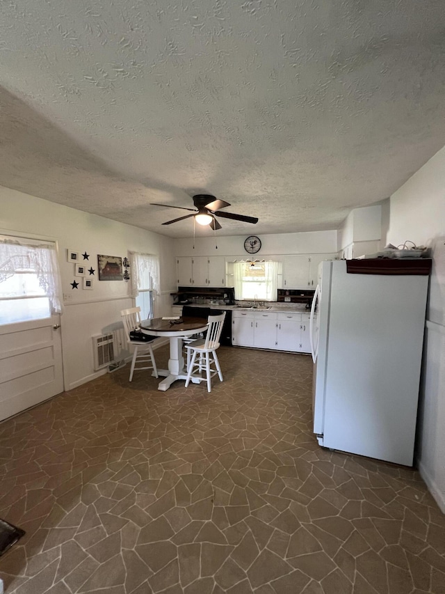 kitchen with white cabinets, white fridge, dark tile patterned floors, and a healthy amount of sunlight