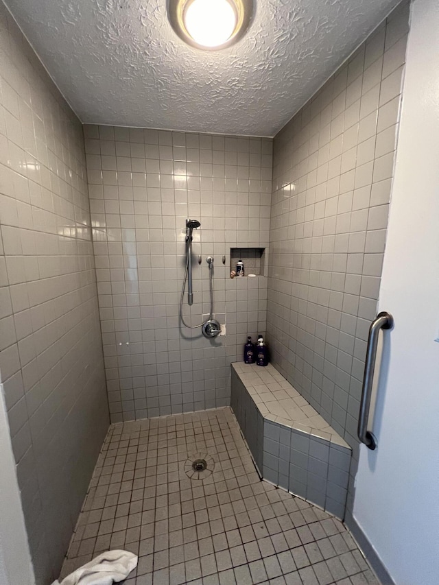 bathroom featuring a textured ceiling and tiled shower