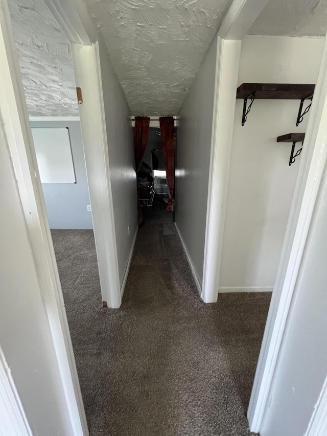 corridor with a textured ceiling and carpet floors