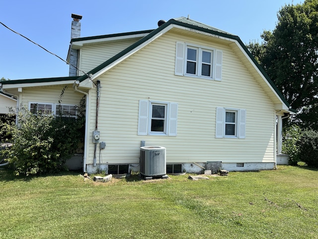 back of property featuring central AC and a lawn