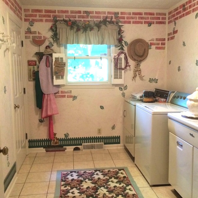 laundry area with brick wall, independent washer and dryer, and light tile patterned floors