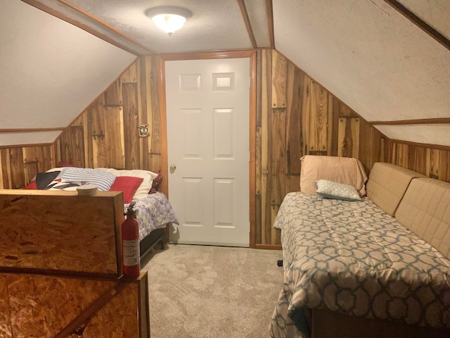 carpeted bedroom featuring lofted ceiling, wood walls, and a textured ceiling