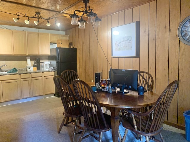 dining room with light wood-type flooring, wood walls, sink, and rail lighting