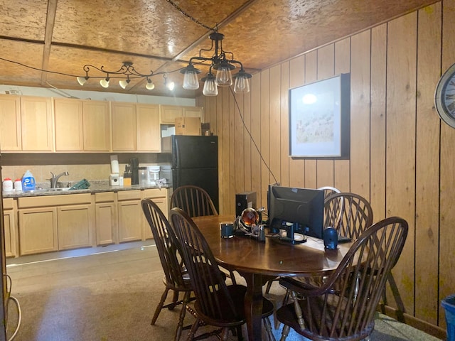 dining room featuring sink, rail lighting, light carpet, and wooden walls