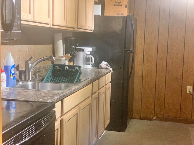 kitchen with light brown cabinets, stove, black refrigerator, light tile patterned floors, and sink