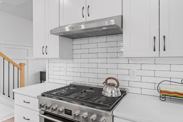 kitchen with light countertops, gas stove, white cabinetry, and under cabinet range hood